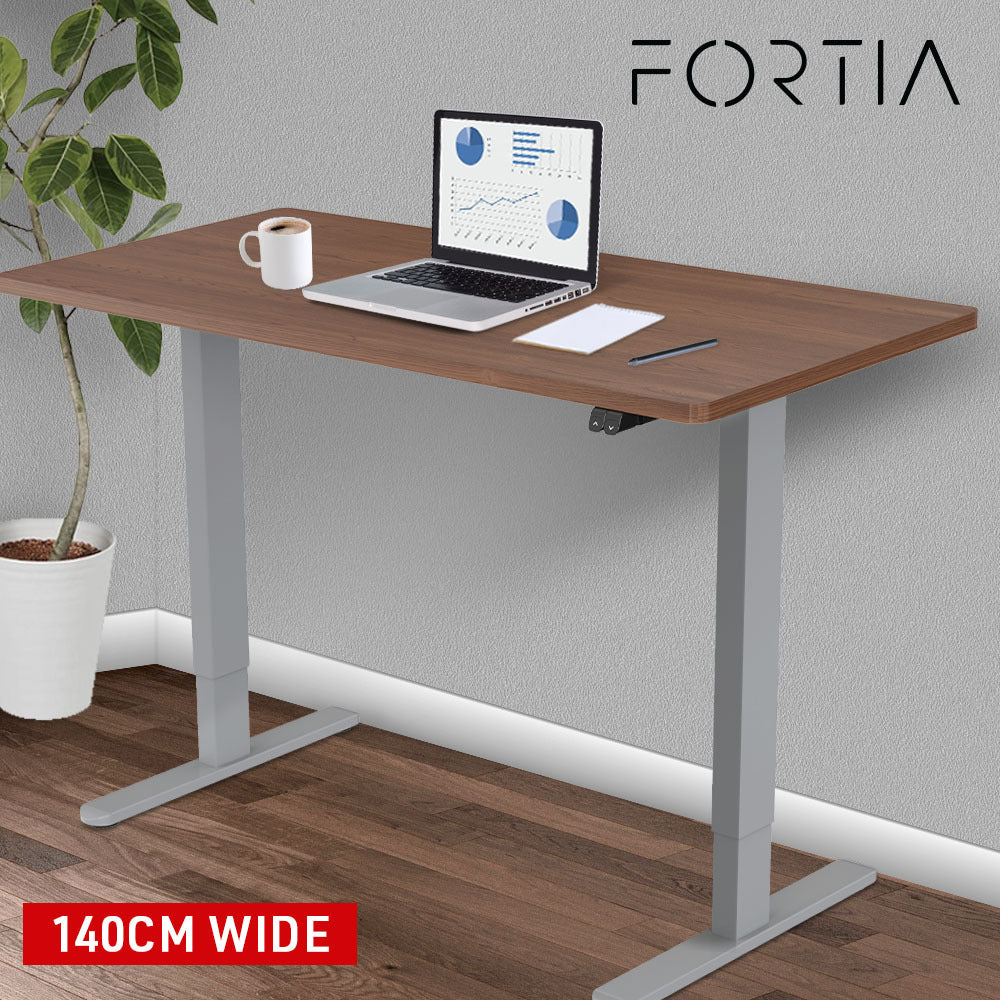 Fortia Sit To Stand Up Standing Desk, 140x60cm, 72-118cm Electric Height Adjustable, 70kg Load, Walnut Style/Silver Frame